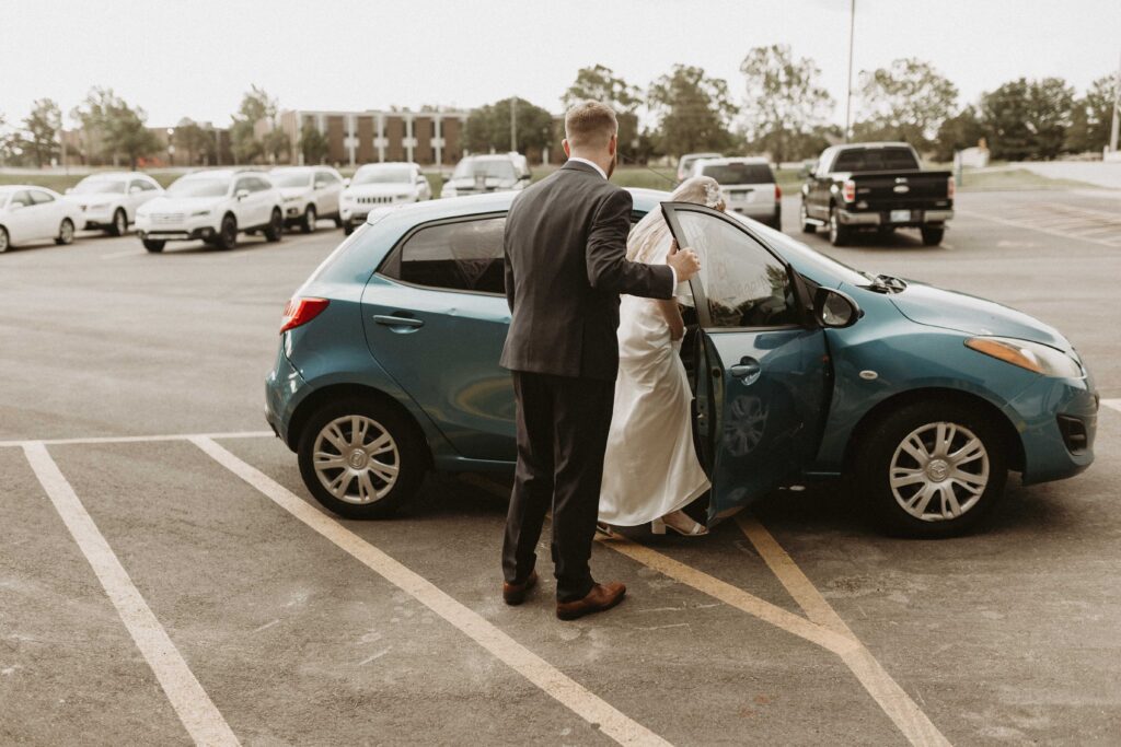 Groom opens car door for bride after send off.