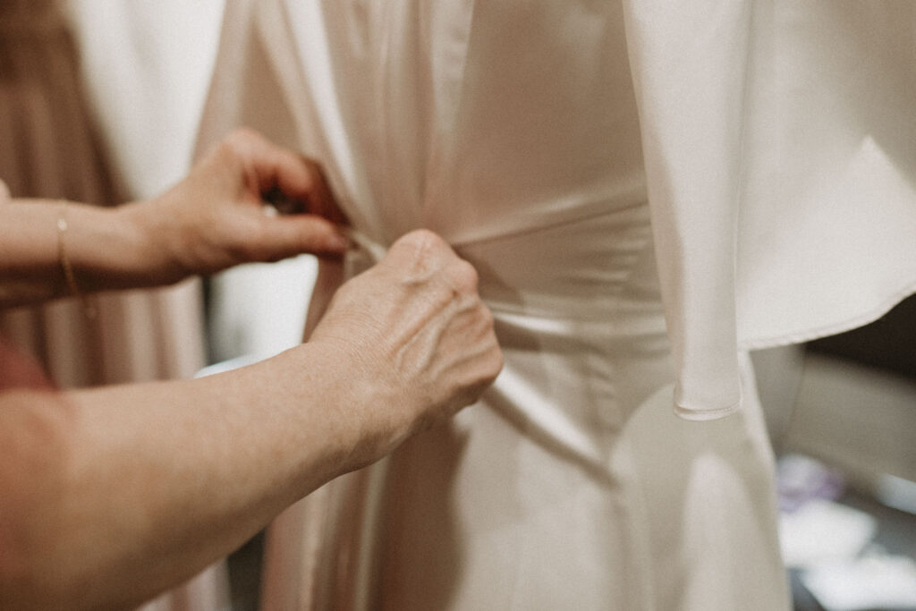 Mother of bride tying her daughter's wedding dress.