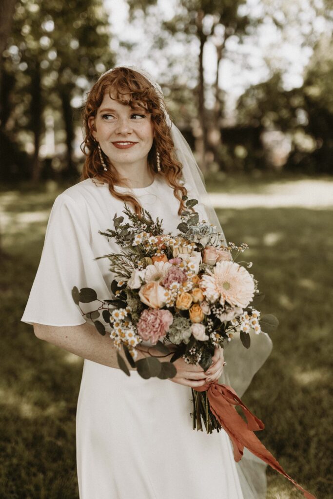 Classy bride wearing a simple, silk gown paired with a vintage veil and a few bling accessories. Her fiery red hair, big blue eyes, and sharp features bring the look to completion.
