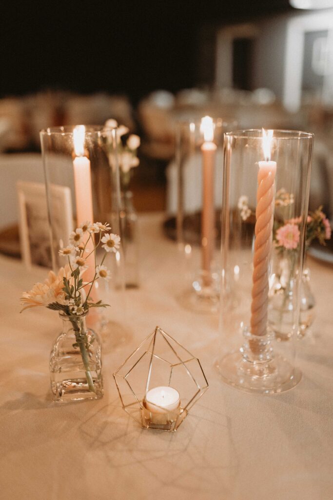 Classy wedding decorations consisting of burnt orange, marigold/saffron, rosy brown, and taupe florals, gold accents, edison lights, and candles.
