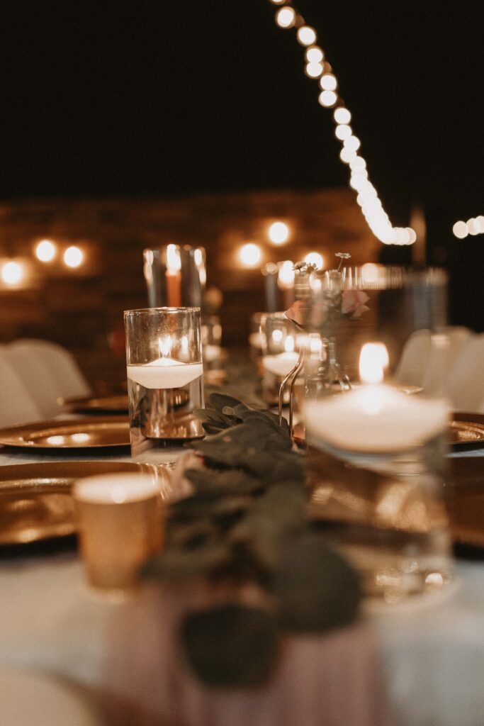 Classy, gold accented reception decorations paired with edison stream lights, florals, and candles.