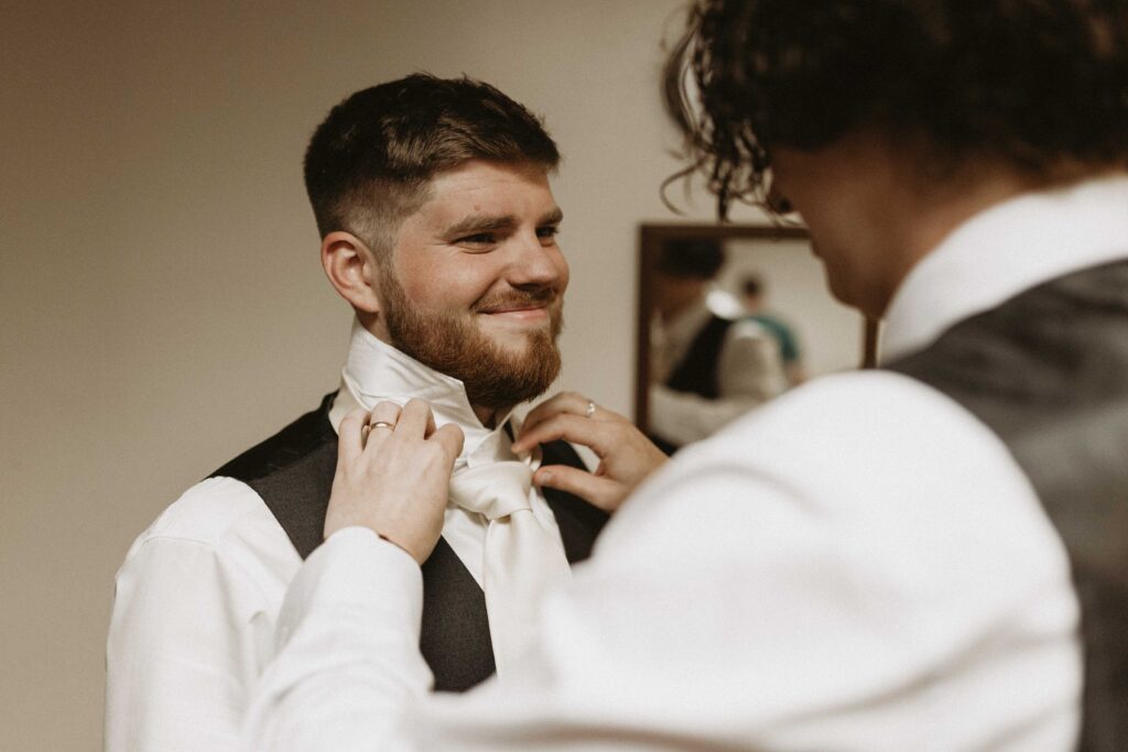 Best man helping groom tie his tie.