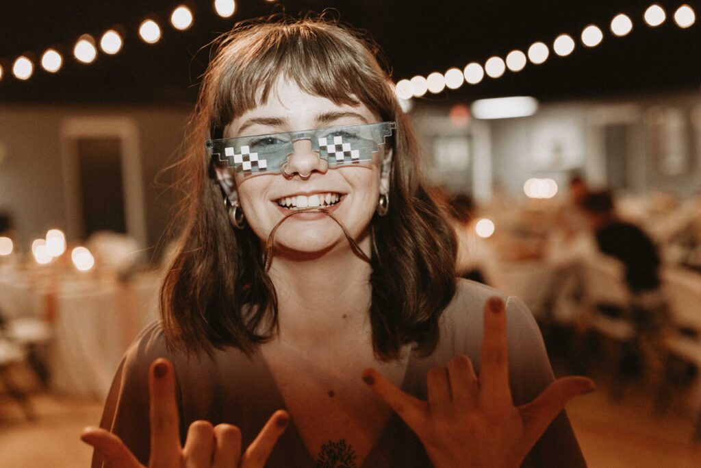Sister of bride wears funny glasses during reception dance party.