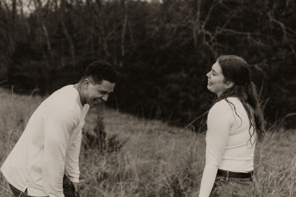 Couple can't stop giggling in an open field together.