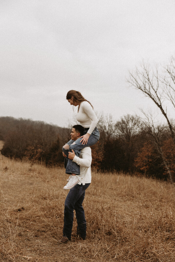 Young girl hops on top of her boyfriend's shoulders.