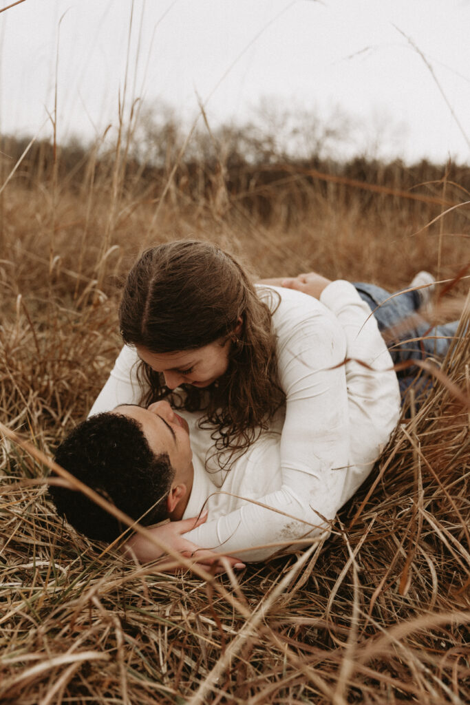 Young couple embrace and roll around on the ground.
