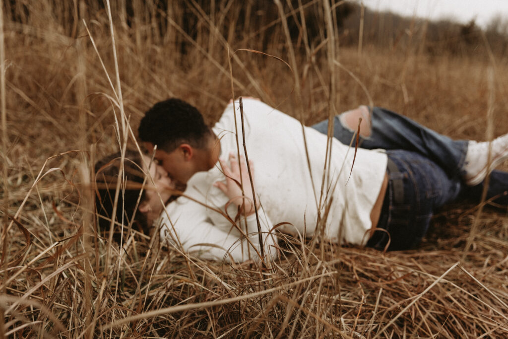 Young couple kiss and roll around on the ground.