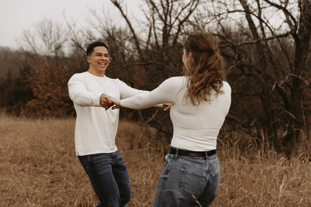 Couple plays ring around the rosey in a field.