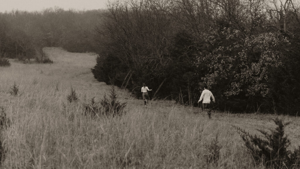 Couple plays tag in an open field.