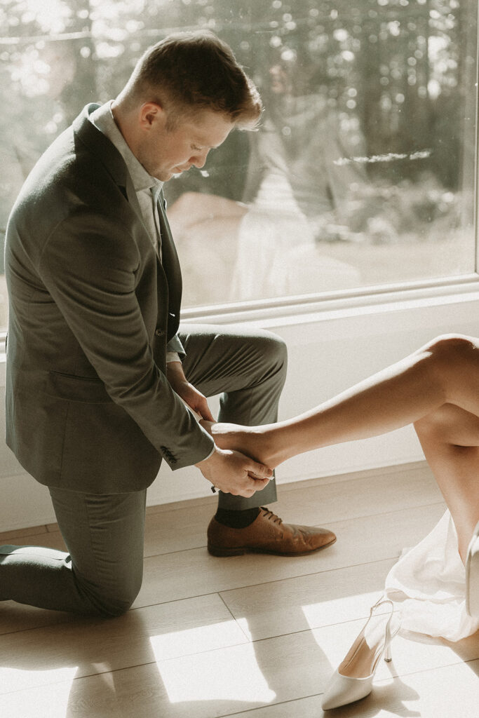 Groom helps bride put on her heels for their southern Oregon elopement.