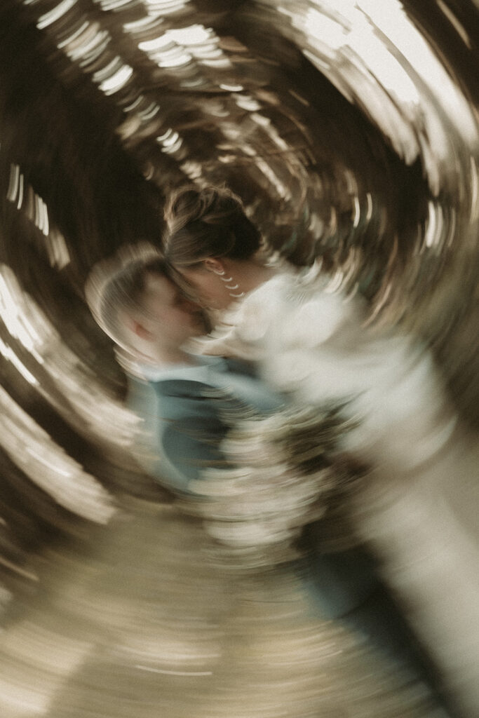 Bride and groom cuddle together in a motion swirl photograph.