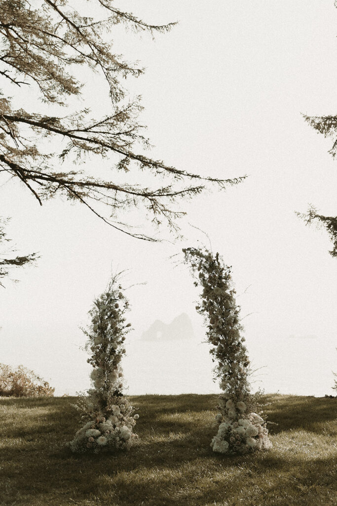 Flower arch with a sea stack rock silhouette background for a Crook Point elopement in Oregon.