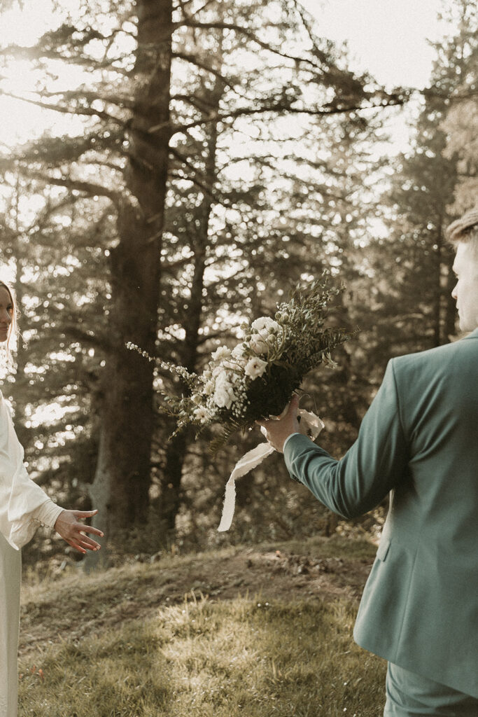 Groom passes off bouquet to bride during their dreamy Crook Point elopement in Oregon.