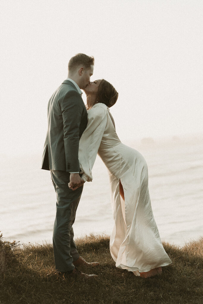 Bride and groom lean in for a kiss during dreamy sunset cliff elopement photos at Crook Point, Oregon.