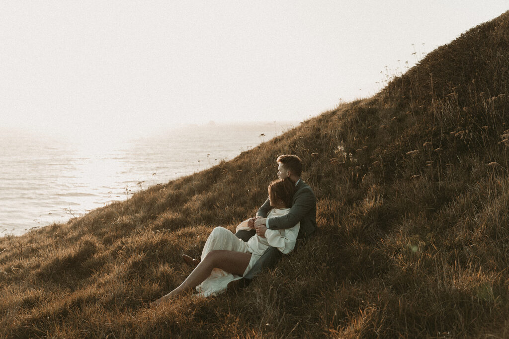 Bride lays into groom on a cliff during dreamy sunset cliff elopement photos at Crook Point, Oregon.