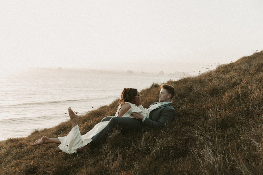 Bride lays on groom during dreamy sunset cliff elopement photos at Crook Point, Oregon.