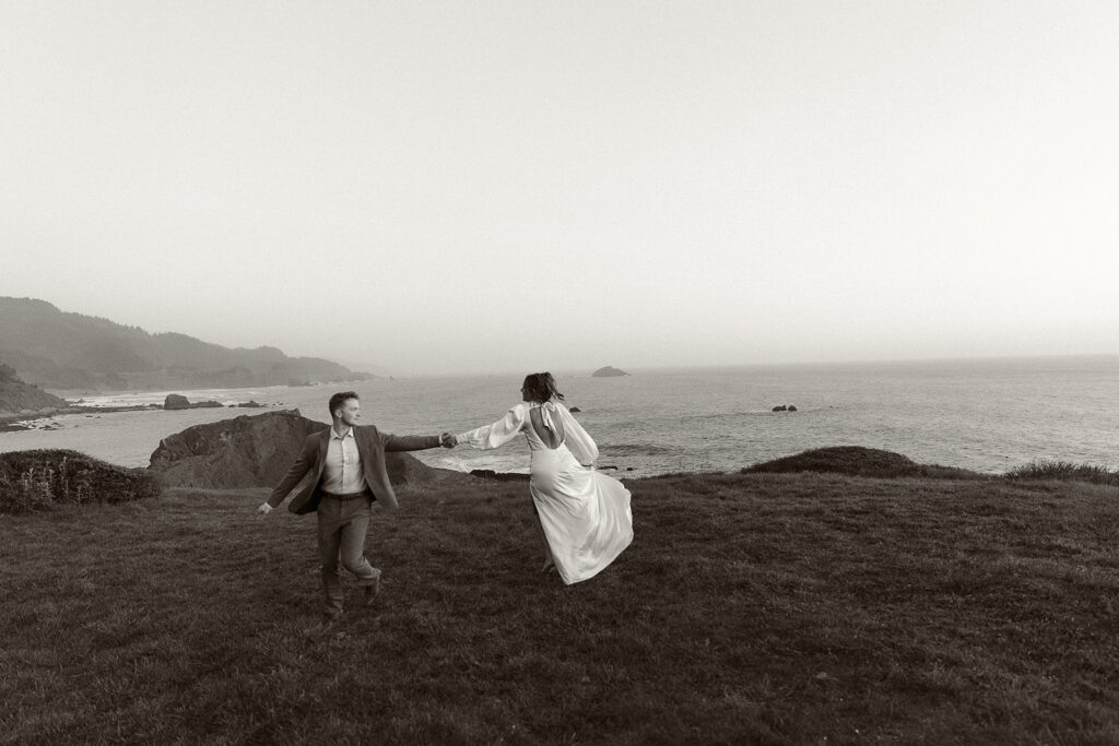 Bride and groom hold hands and twirl during dreamy sunset cliff elopement photos at Crook Point, Oregon.
