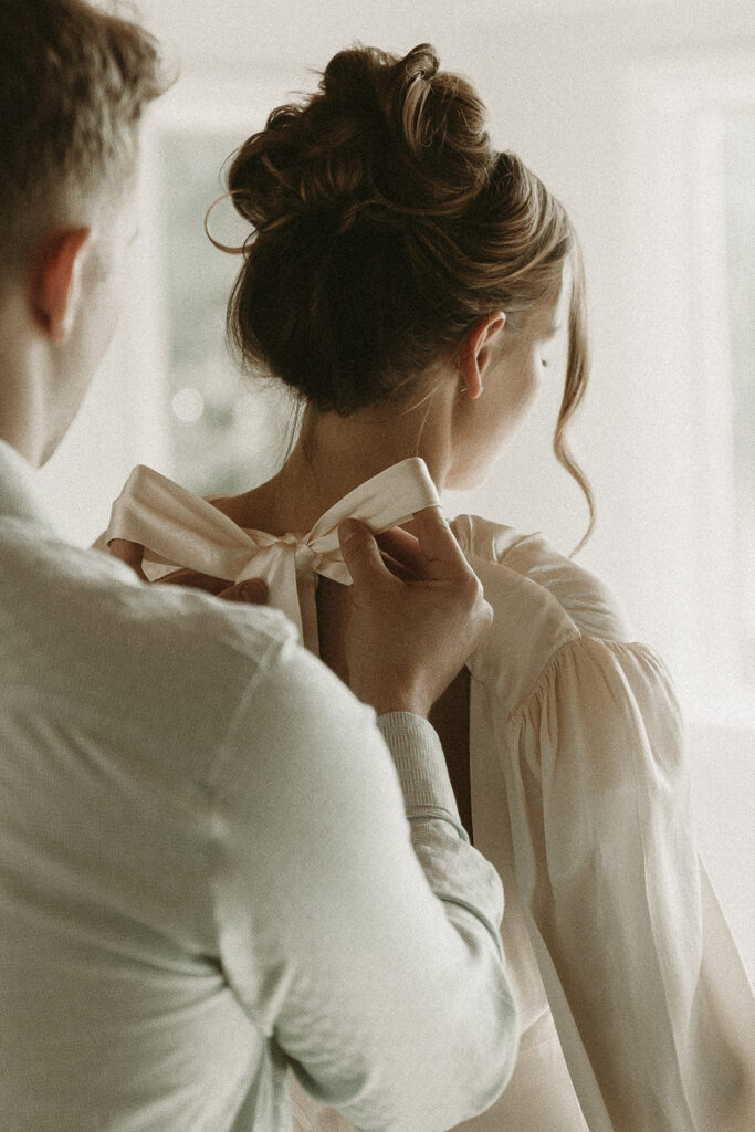 Groom ties his bride's dress bow for their southern Oregon elopement.