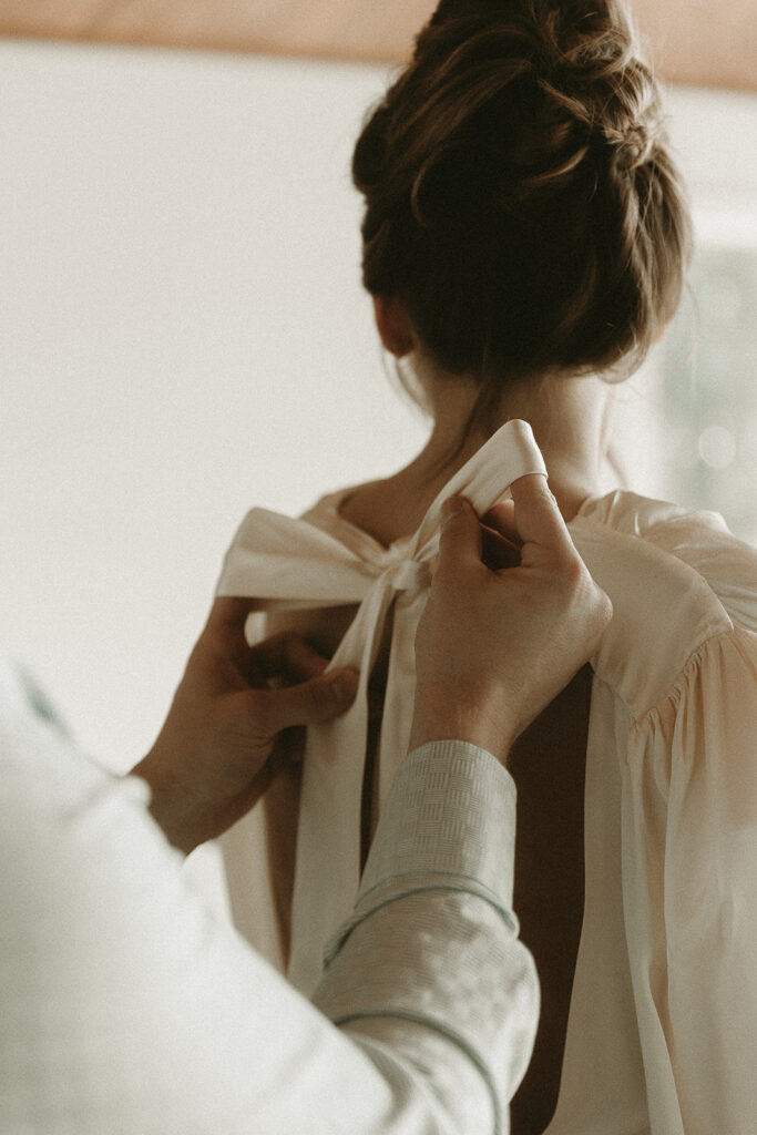Groom ties his bride's dress bow for their southern Oregon elopement.