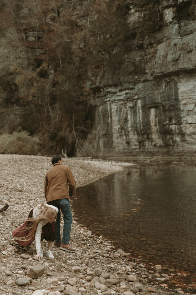 Young couple take turns skipping rocks in Buffalo River, Arkansas.