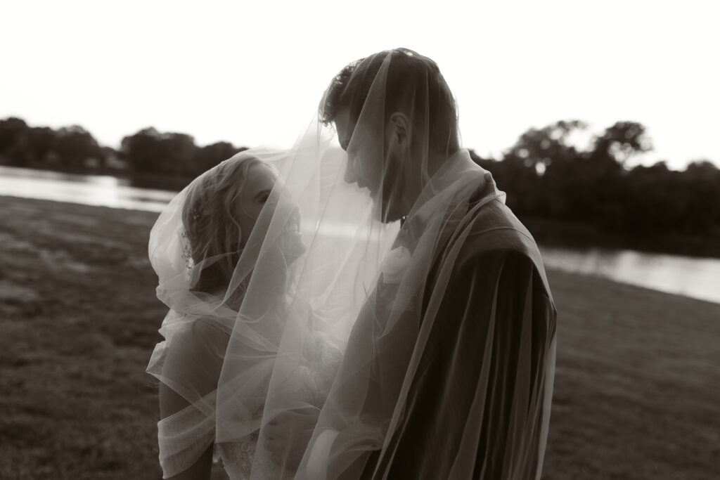 Newly married couple share some giggles under the bride's veil during their sunset photos with Abby Ree Photography.